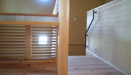 玄関の吹き抜けと隣り合う、木格子と鉄の手すりが美しい階段